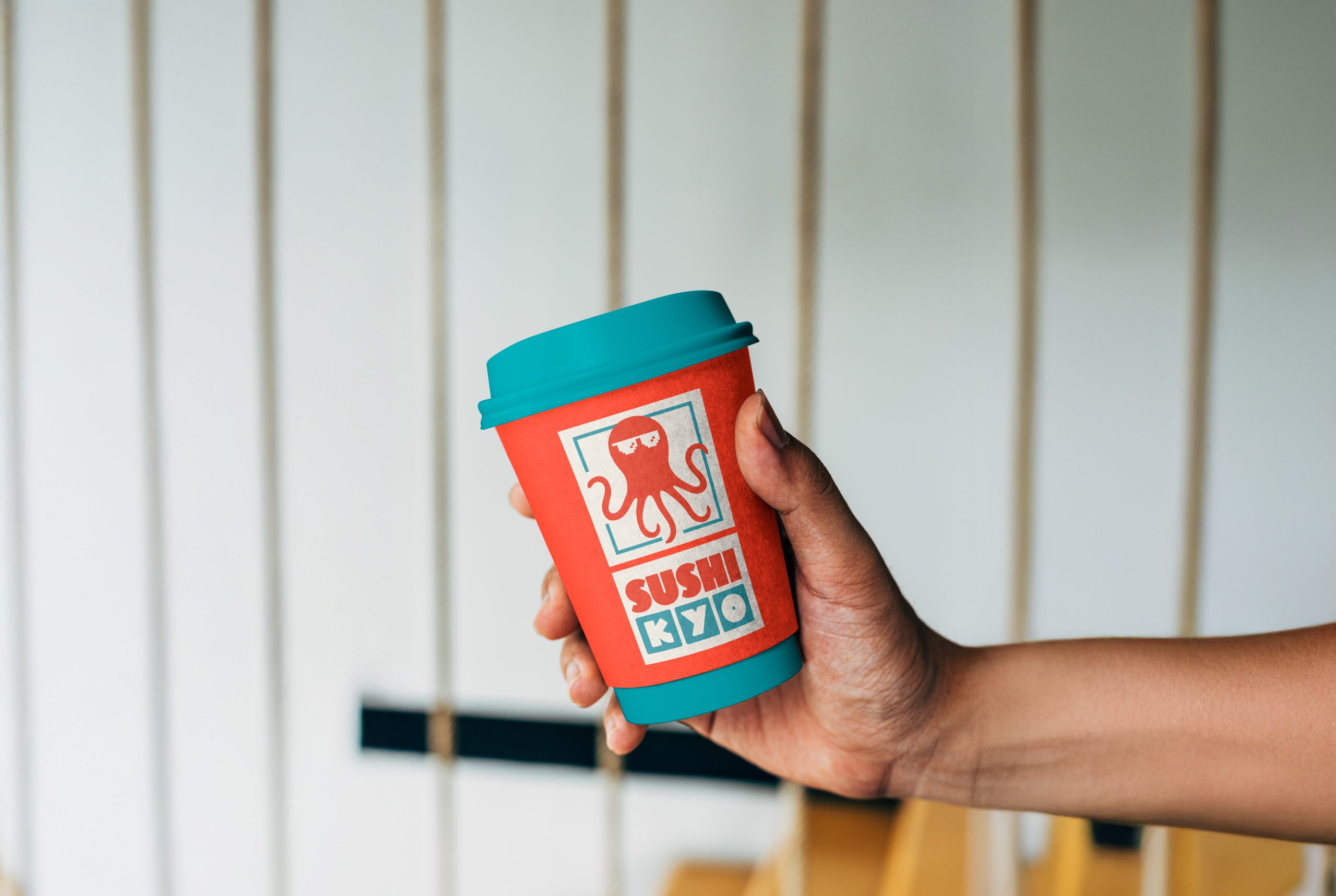 Branded takeaway coffee cup with sushi restaurant logo and bold colours