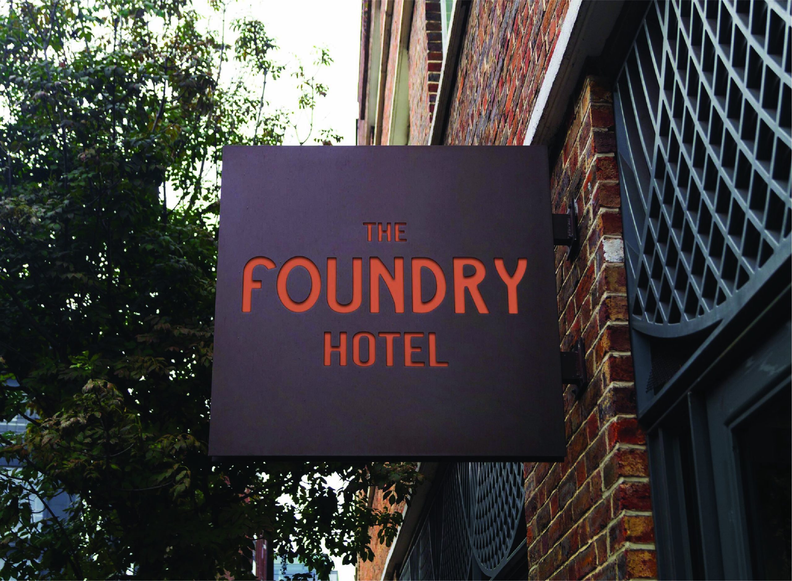 Exterior hotel sign displaying The Foundry Hotel branding on a historic brick building