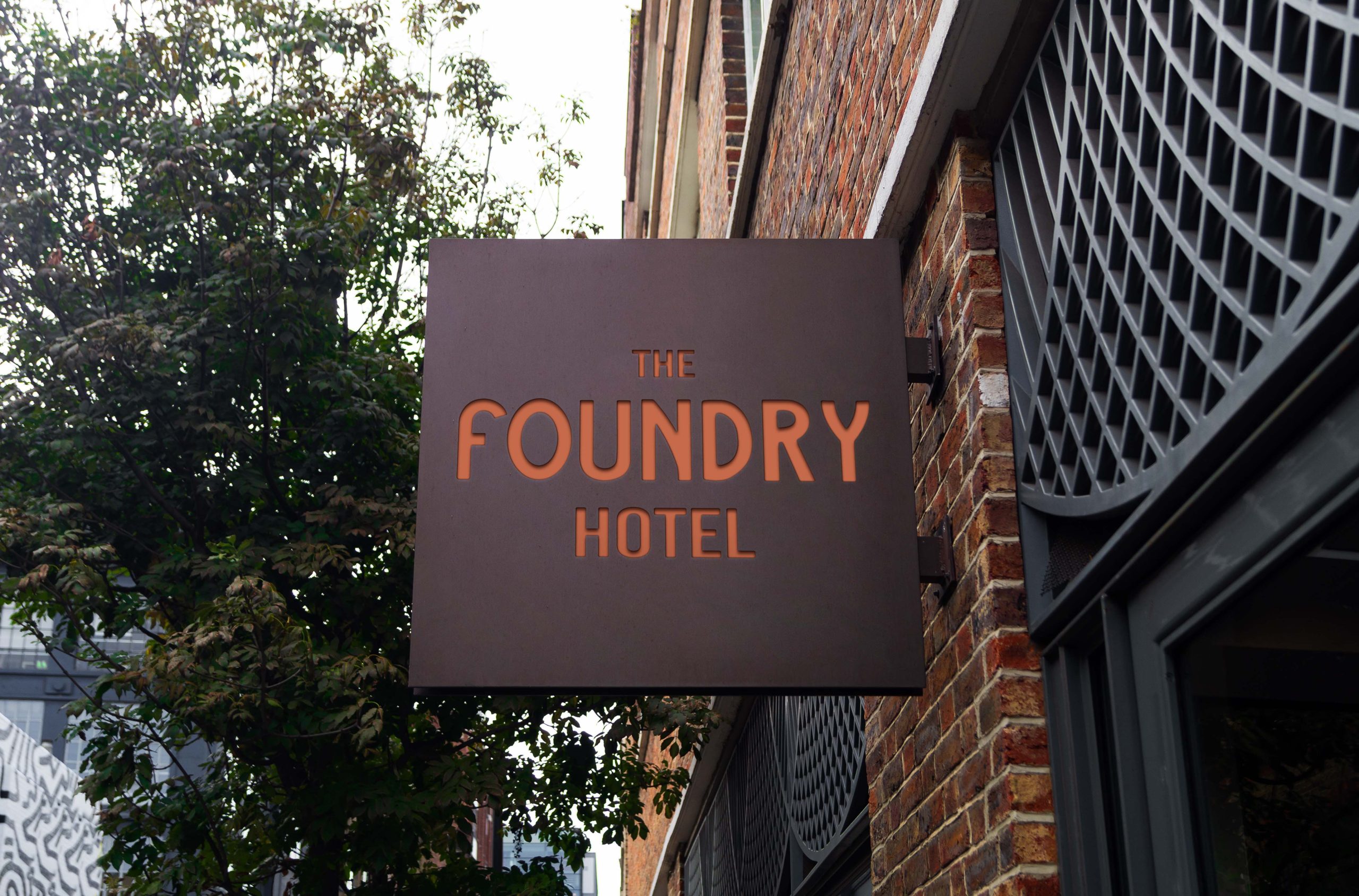 Exterior hotel sign displaying The Foundry Hotel branding on a historic brick building