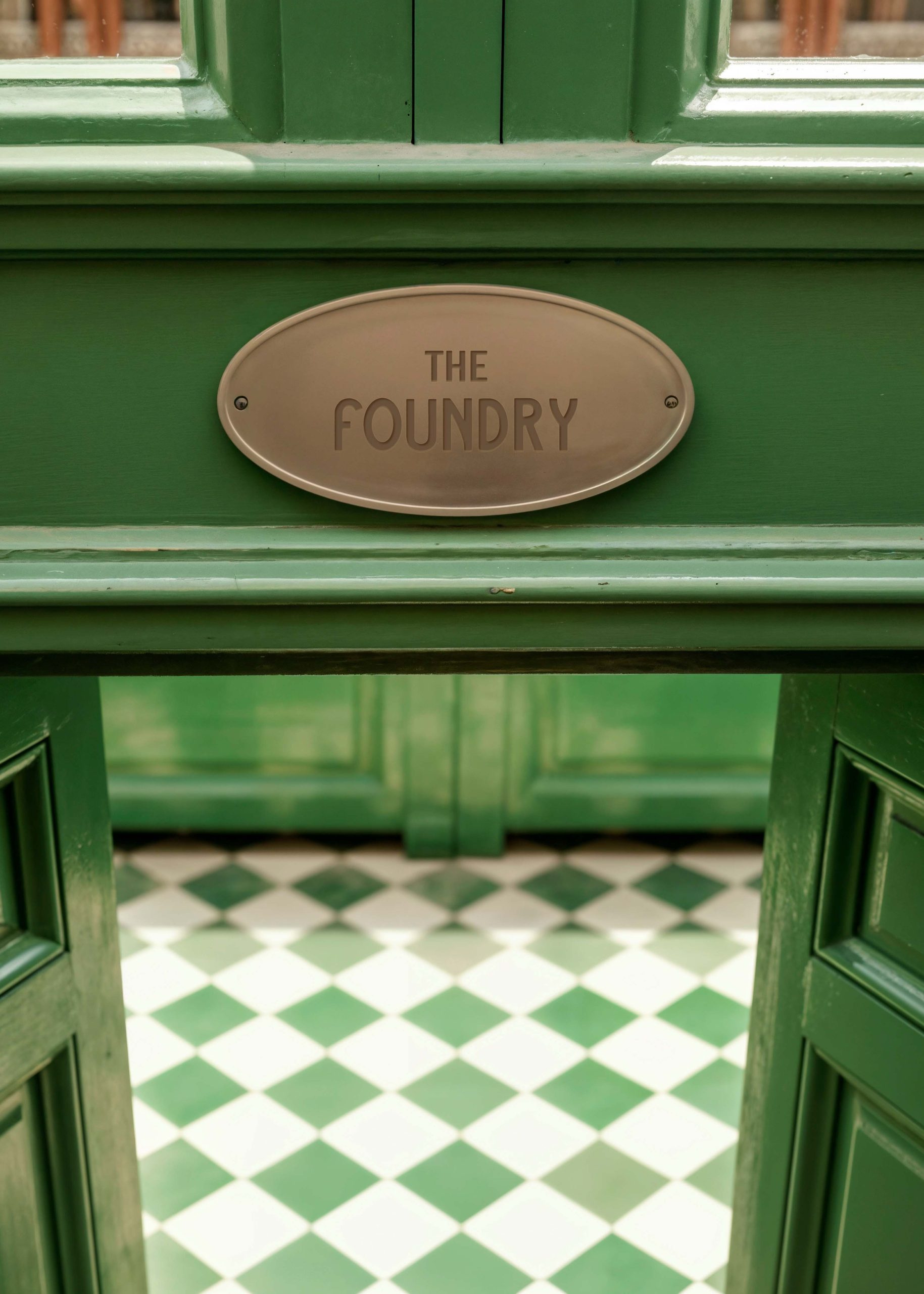 Branded hotel entrance plaque mounted on a green doorway
