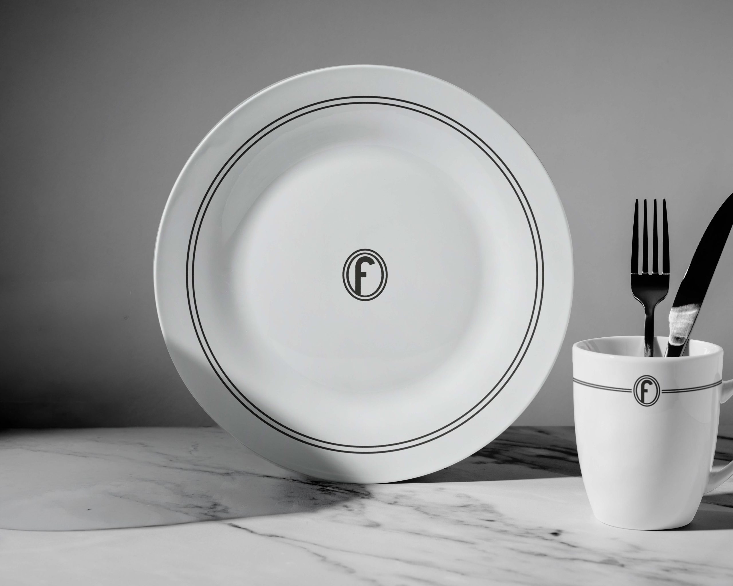 Branded hotel tableware including plate and mug with custom monogram