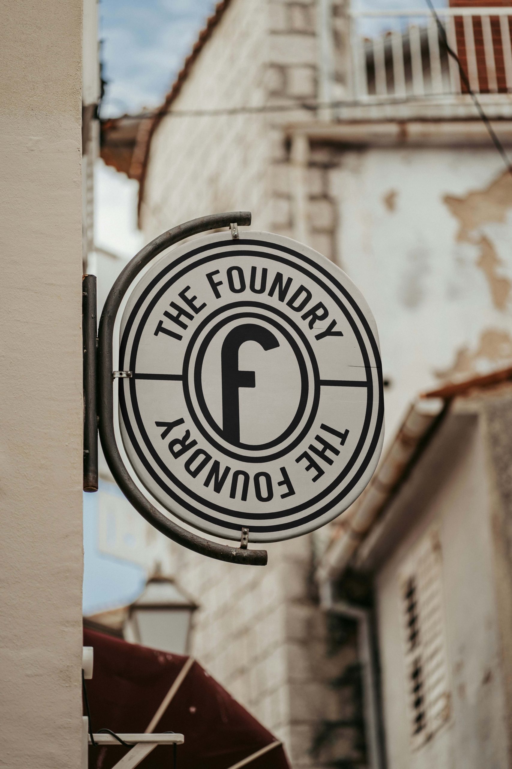 Circular hanging hotel sign displaying The Foundry Hotel monogram logo