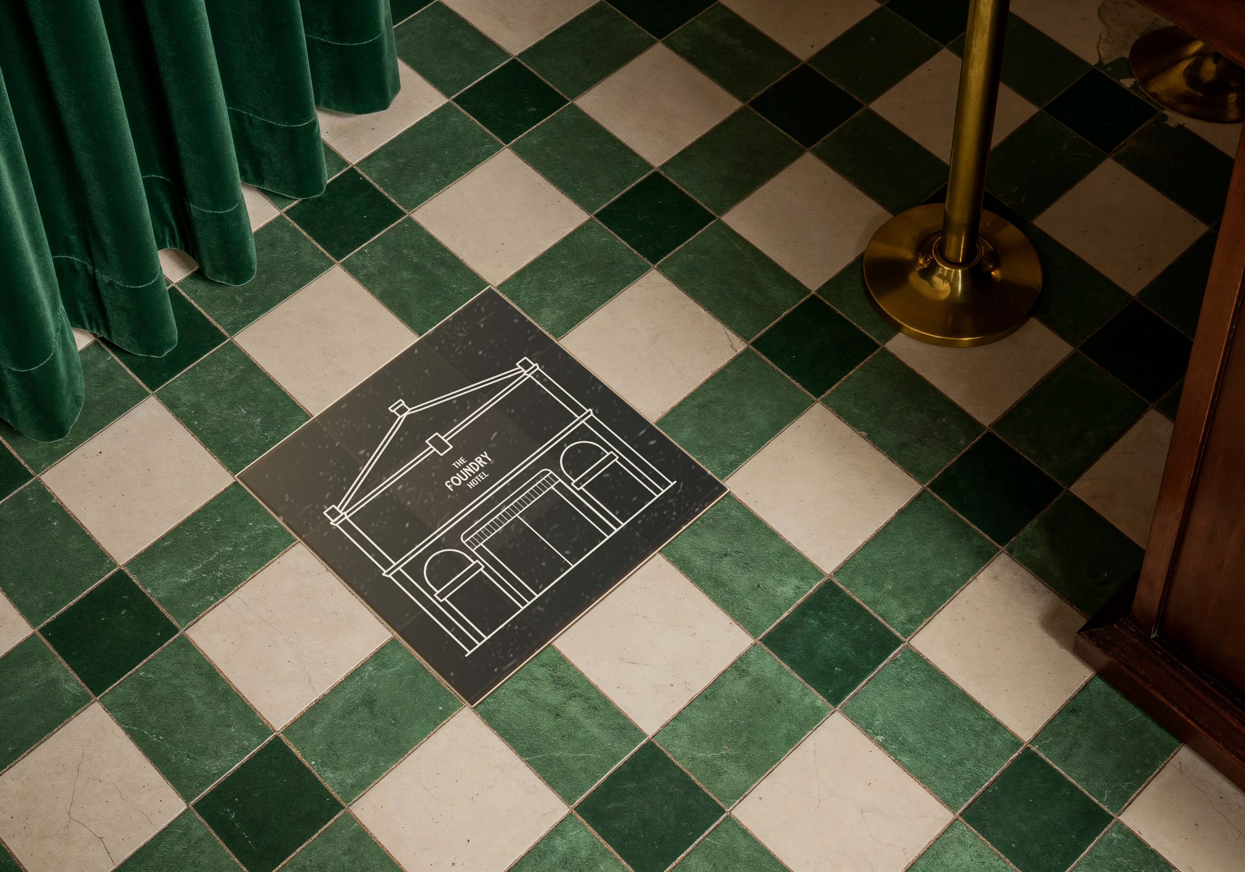 Branded floor graphic featuring The Foundry Hotel building illustration on checkered tile flooring