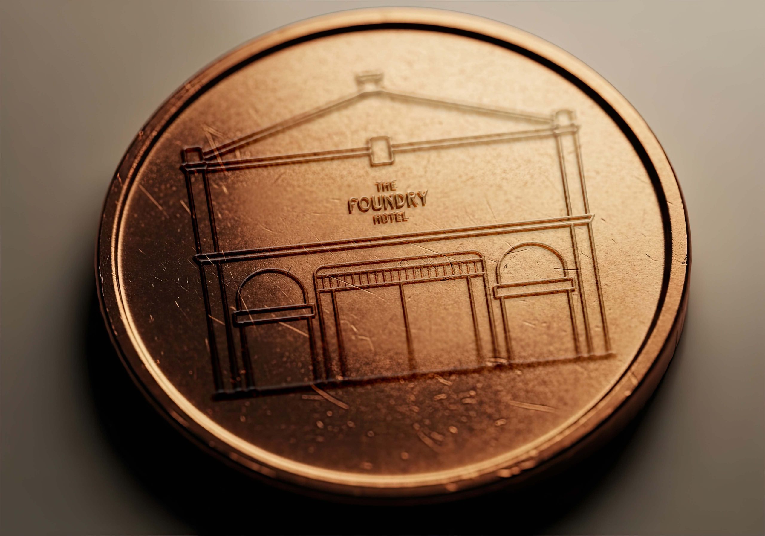 Metal hotel token engraved with The Foundry Hotel building illustration